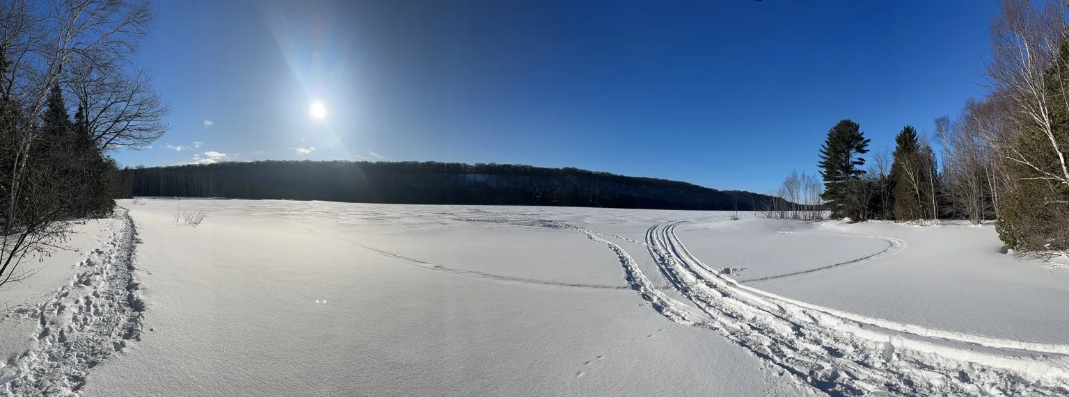 Snow tracks along a sunny frozen lakeshore
