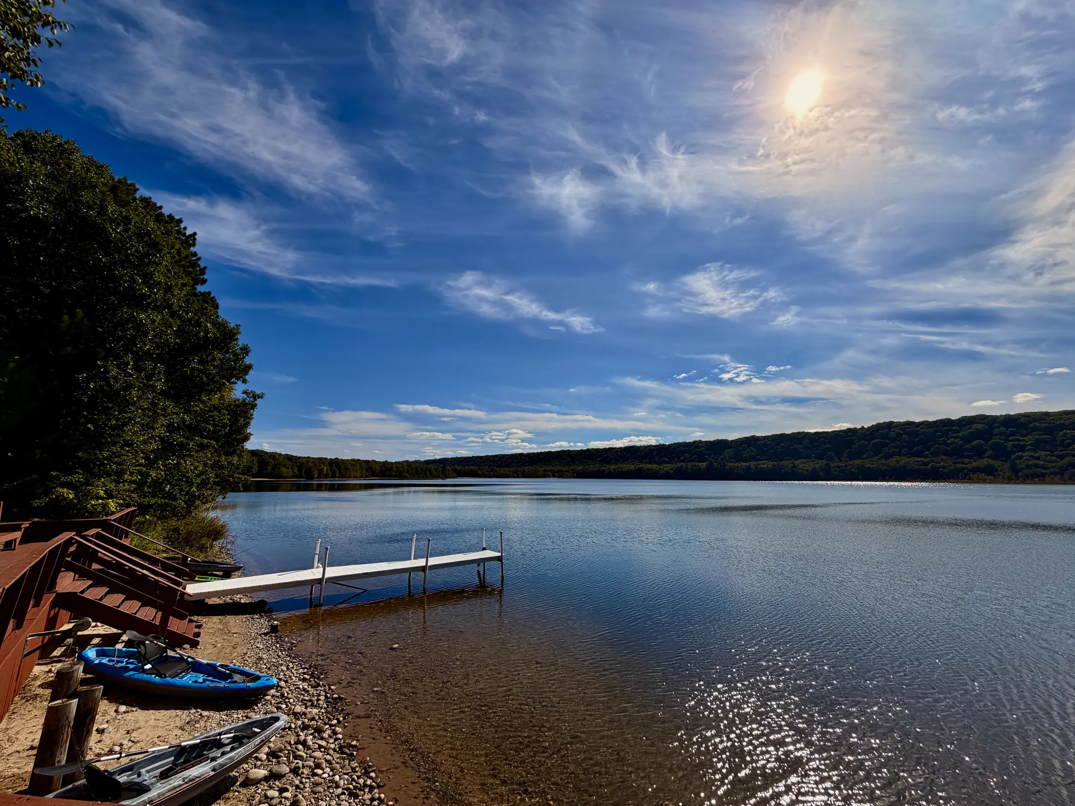 Full view from the deck across the shoreline and dock toward the sun over Monocle Lake