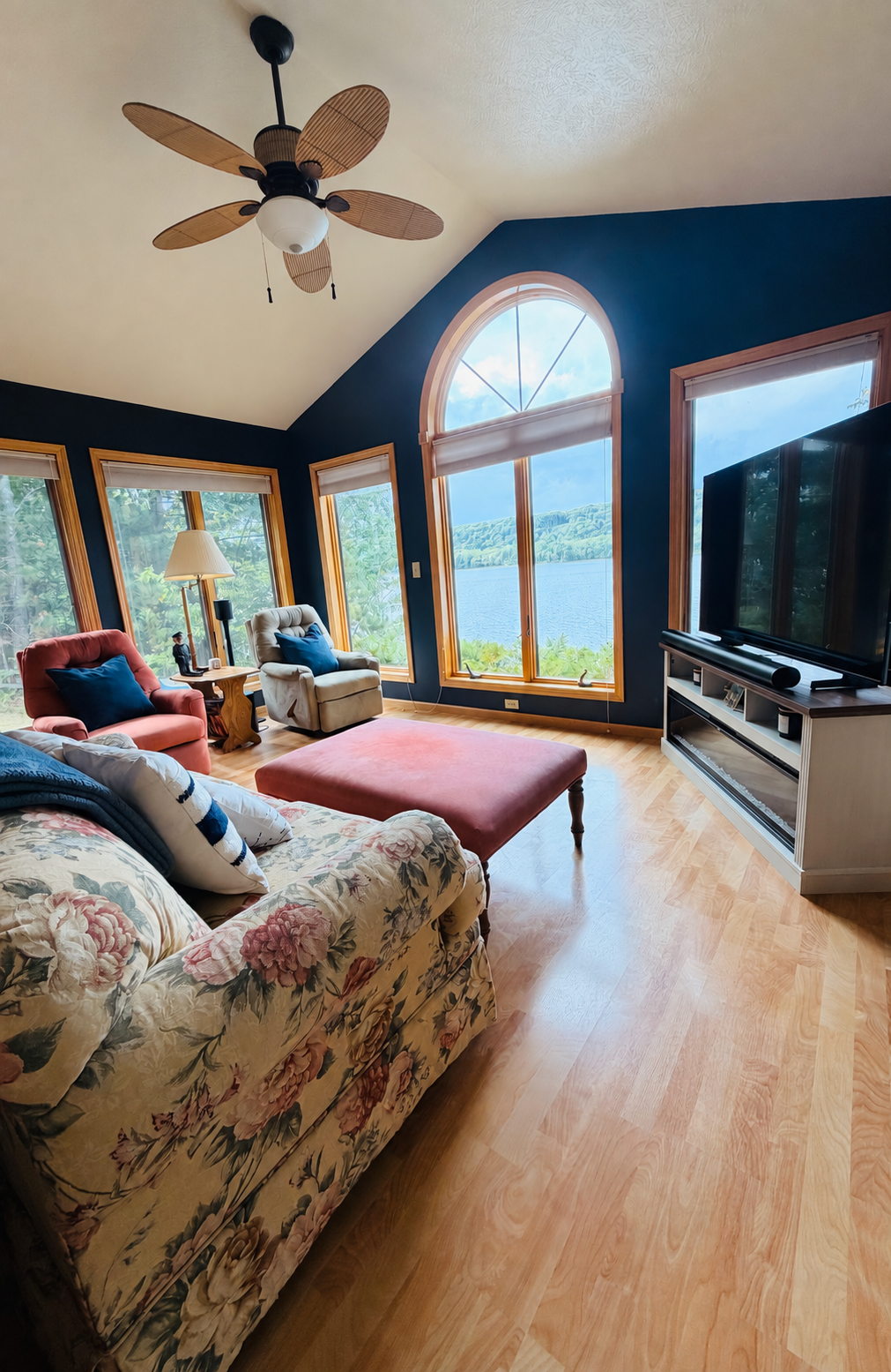 Second living room from the sofa, with arched lake-facing windows, television and ceiling fan