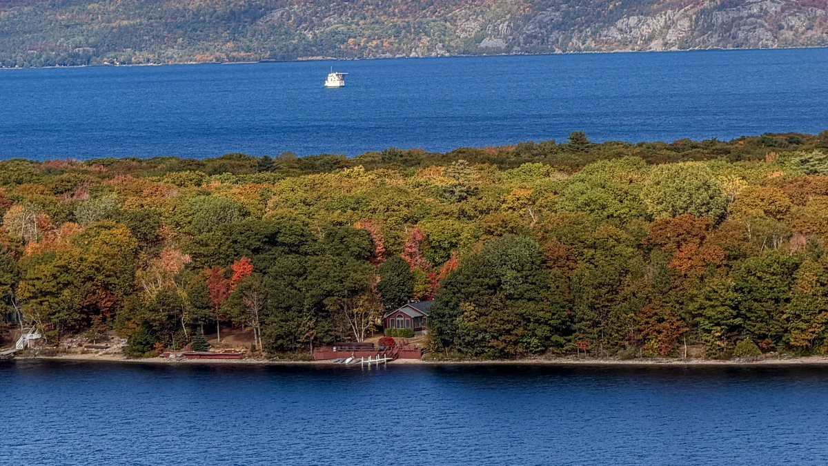 Wide view of The Loon Hollow, foreground lake, fall forest and distant freighter